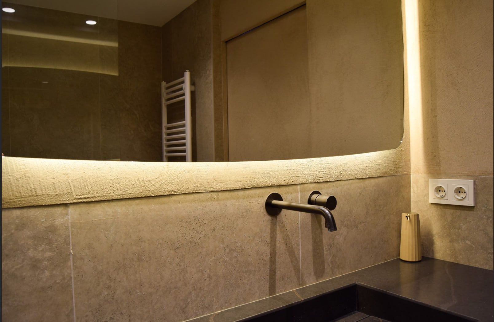 Después: Baño de piedra natural con espejo retroiluminado y grifería negra empotrada