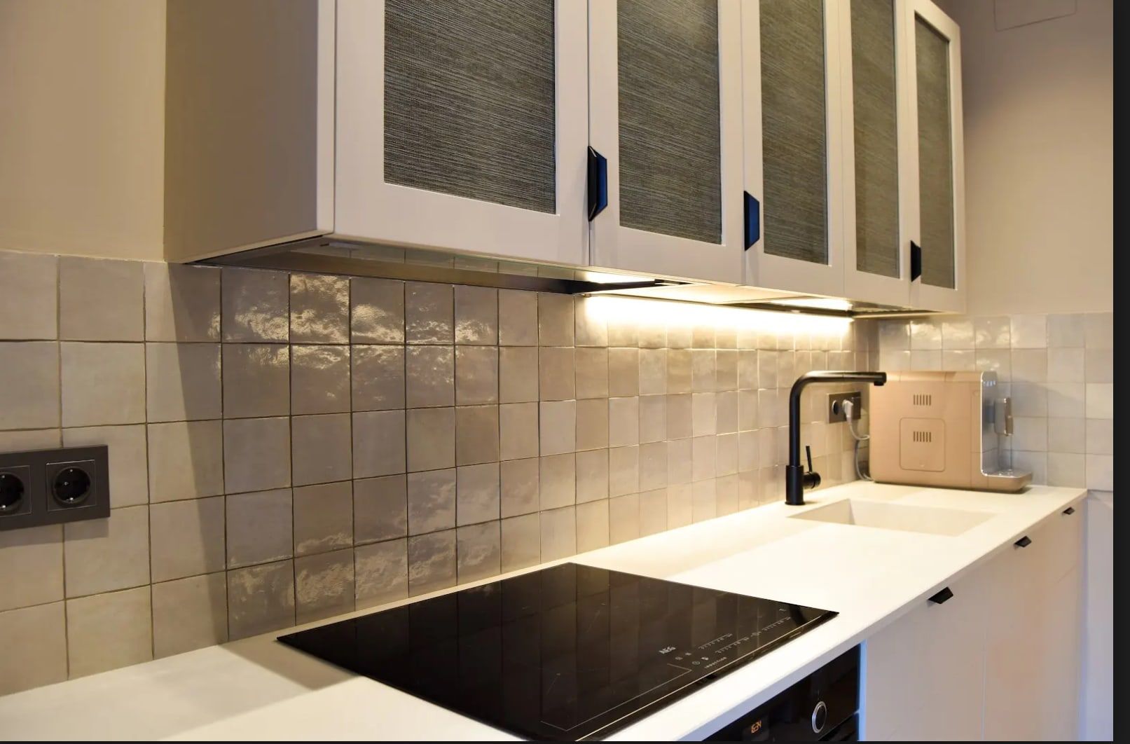 Cocina con azulejo artesanal, placa de inducción y grifo negro