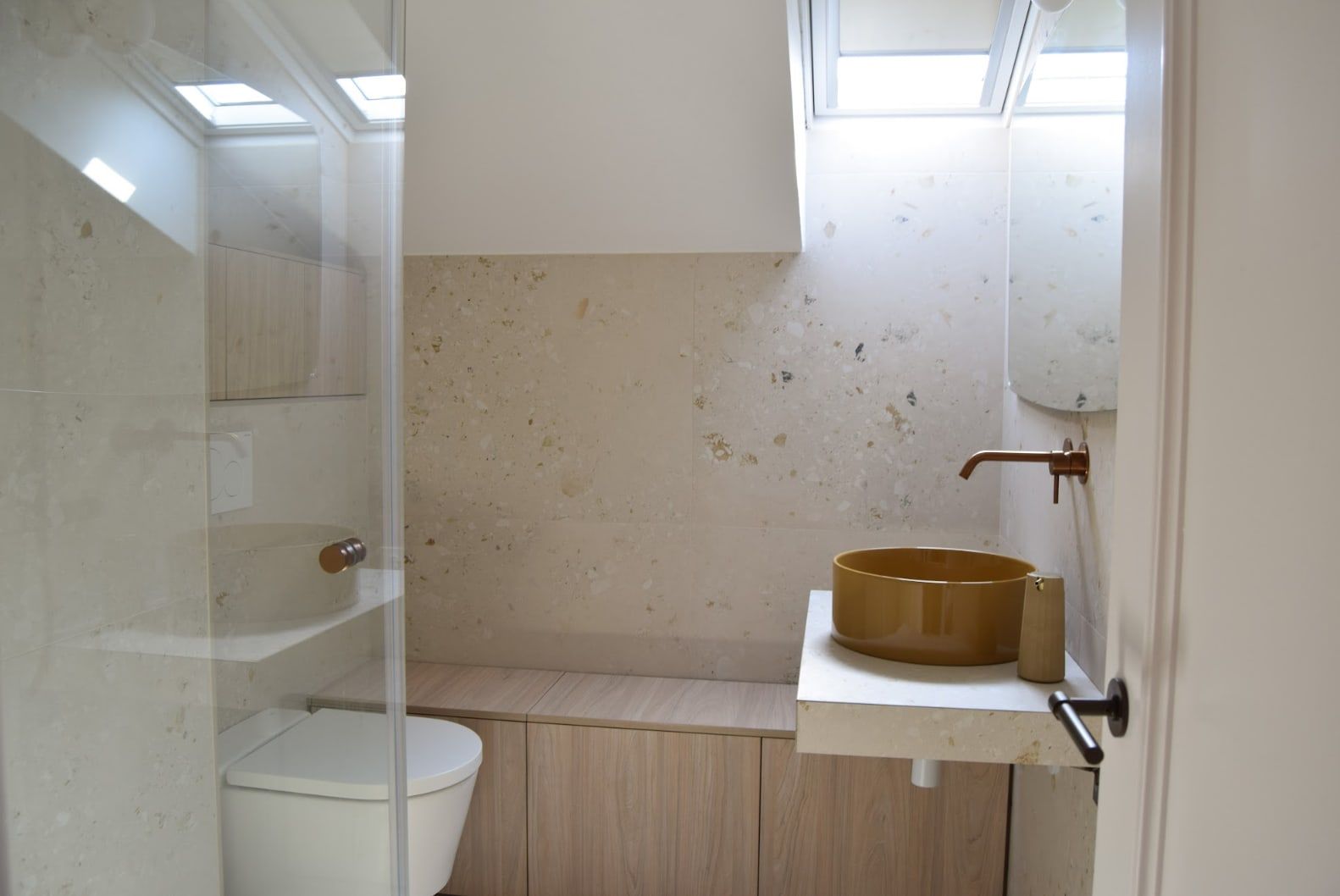 Aseo bajo cubierta con lavabo de bronce y paredes de piedra