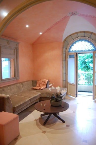 Salón con techo abovedado, puerta en arco y sofá de terciopelo