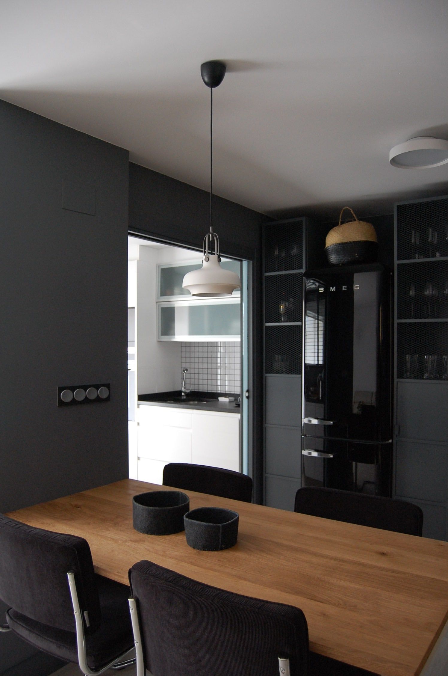 Mesa de comedor de roble con lámpara colgante y la cocina al fondo