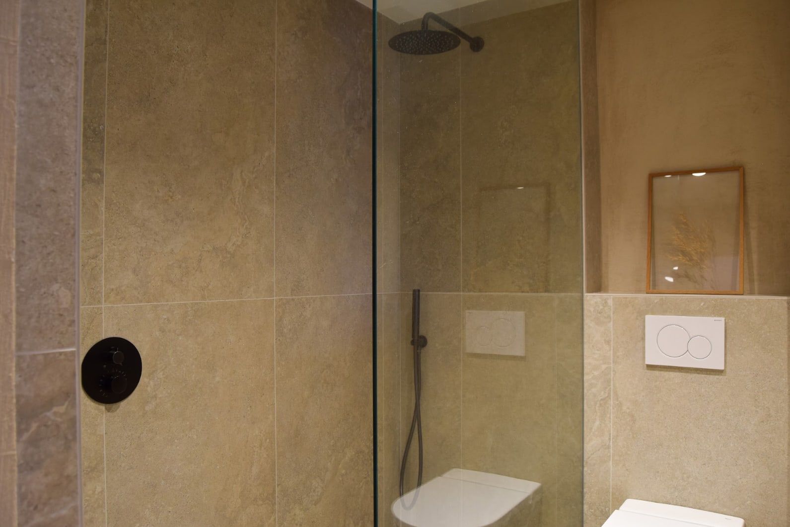 Ducha de obra con mampara de cristal y revestimiento de piedra